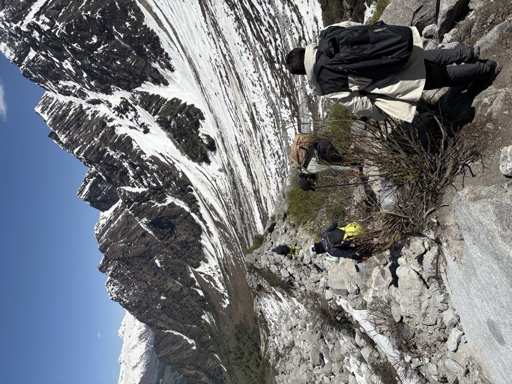 Trekkers crossing a boulder field on the Beas Kund trail